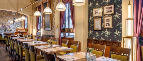Un restaurant doté de plusieurs tables, de chaises, de luminaires suspendus et d’un piano.