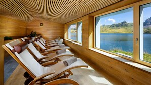 Un cuarto de spa con paredes de madera y ventanas amplias que dan a un lago.