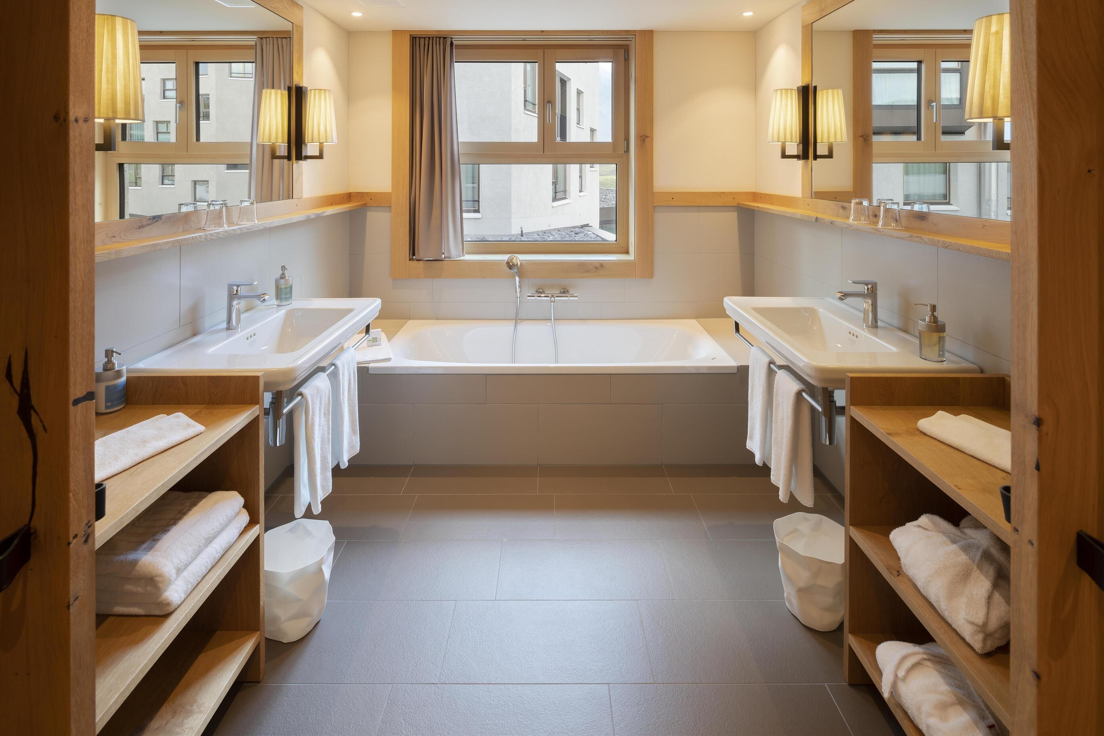 Un baño moderno con dos lavamanos, una bañera y un ventanal.