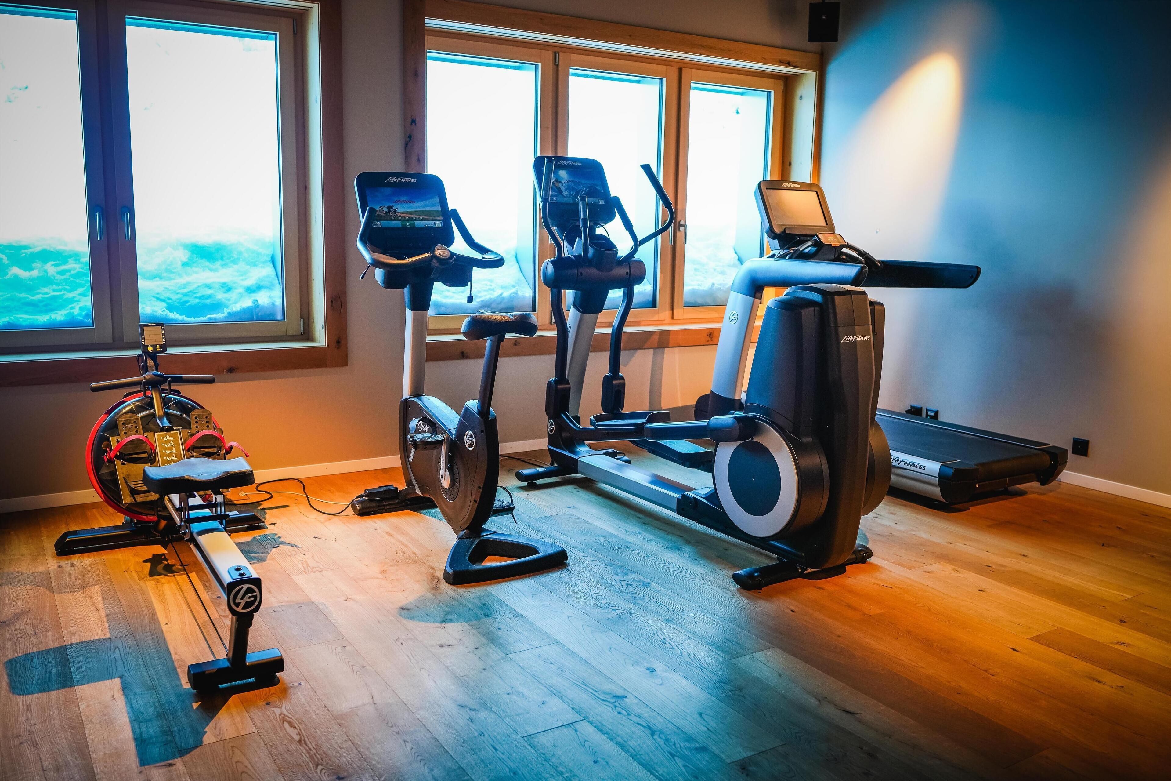 A home gym with cardio equipment including an elliptical, a stationary bike, and a treadmill.