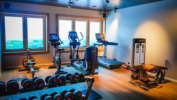 Un gimnasio con máquinas de cardio, pesas y una máquina de remo.