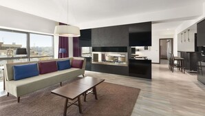 A modern living room with a sofa, coffee table, and a large window offering a city view. - Ramada by Wyndham Pitesti (Pitesti)