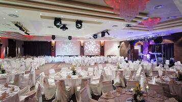 A banquet hall with round tables, white tablecloths, and chairs with white sashes.