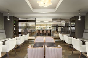 Een moderne lobby met een centrale zithoek, een receptiebalie en uitzicht op het restaurant.
