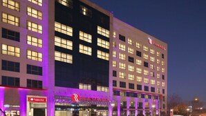 A multi-story hotel with a prominent 'RAMADA' sign, illuminated windows, and a well-lit entrance area. - Ramada by Wyndham Pitesti (Pitesti)