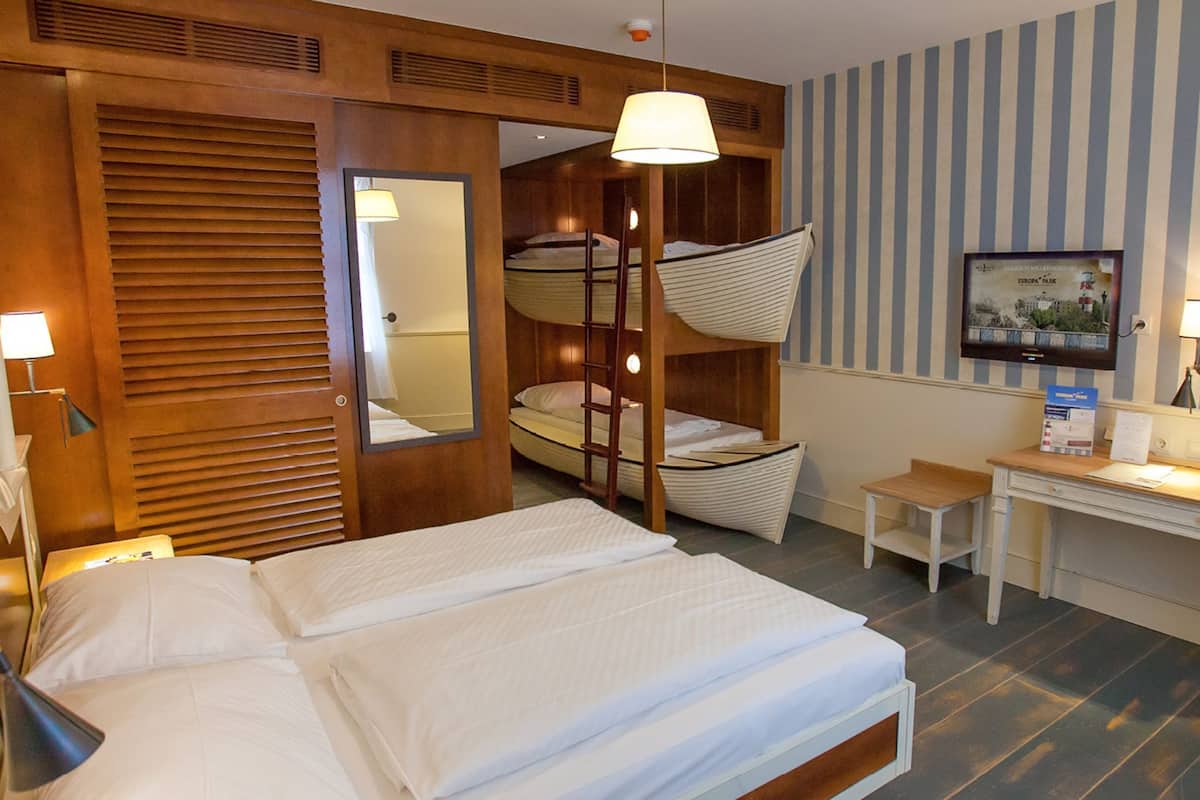 Ein Hotelzimmer mit Etagenbett, Schreibtisch, Stuhl, Lampe und einem gerahmten Bild an der Wand.