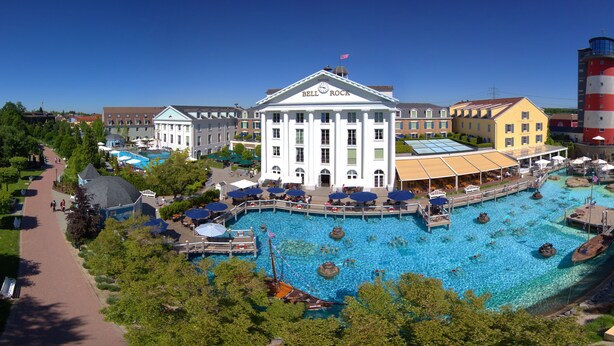Ein Resort mit großem Schwimmbad, einem Glockenturm und einem Leuchtturm.