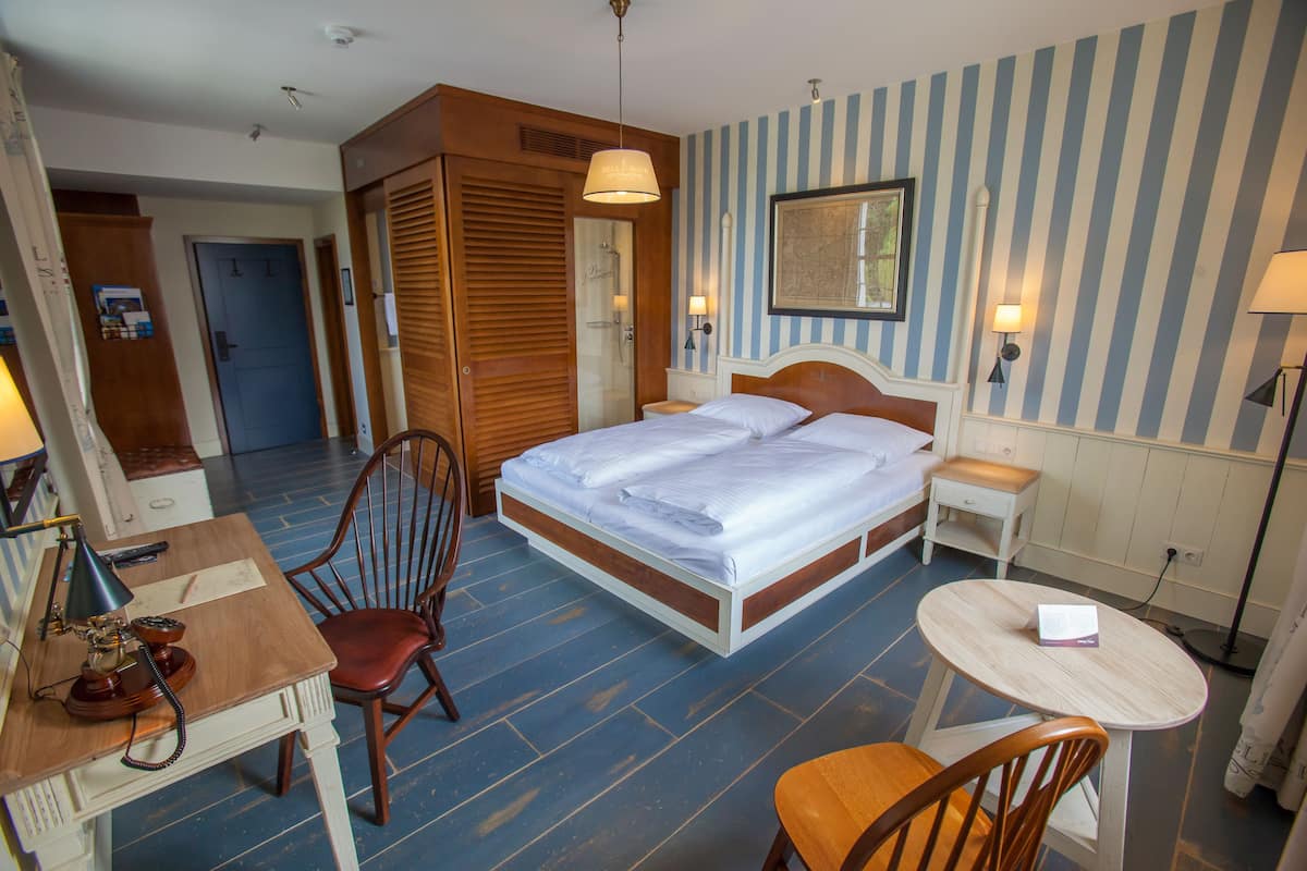 Ein Hotelzimmer mit einem Bett, einem Schreibtisch, einem Sessel, einem kleinen Tisch und einem Duschbereich.