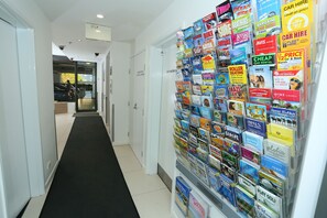 Un couloir avec un tapis noir et un mur recouvert de diverses annonces colorées pour la location de biens immobiliers.