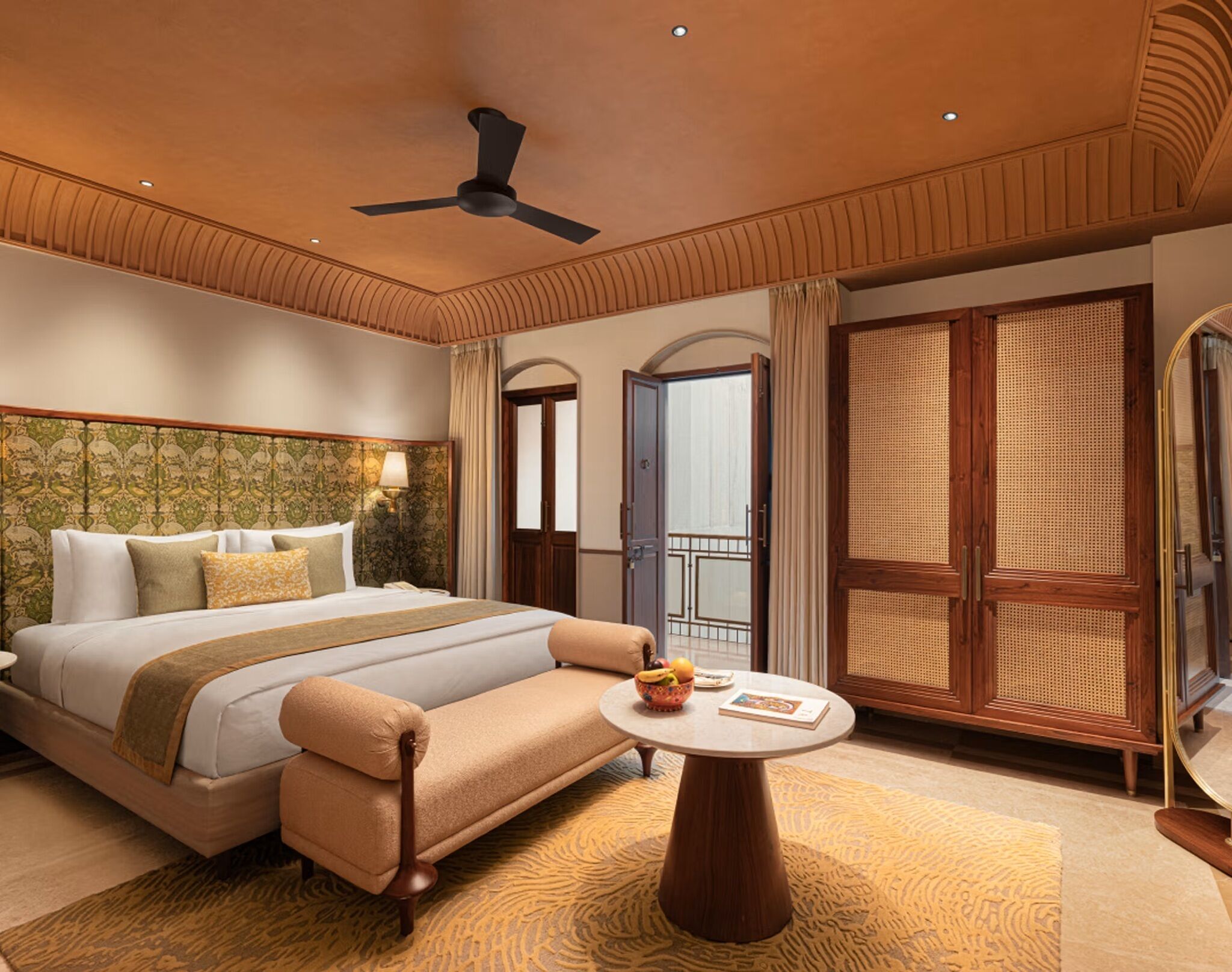 A hotel room with a bed, a sofa, a round table, a ceiling fan, and a large window with a view.