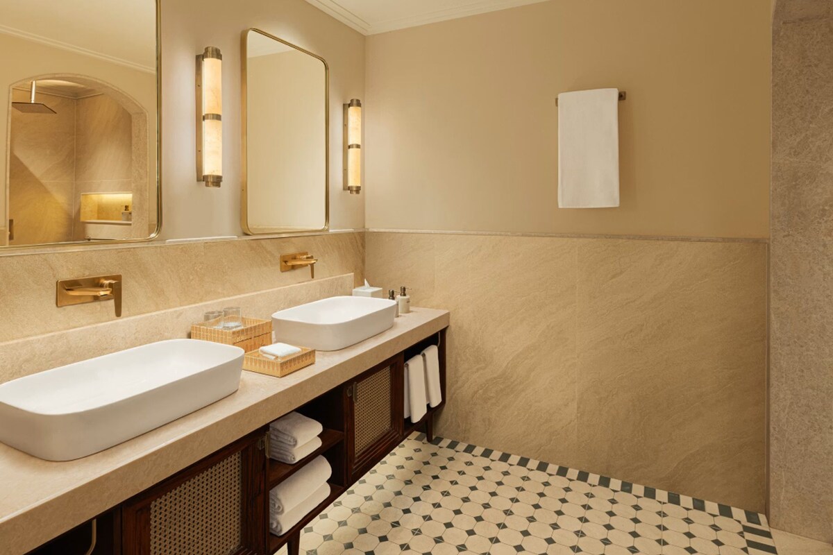 A modern bathroom with two sinks, a large mirror, and a towel rack.