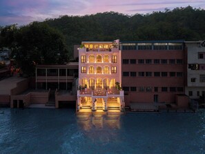 A multi-story hotel with a pool in front, surrounded by trees and a hill in the background. - Hari Ganga Niwas, Haridwar \- IHCL SeleQtions (Haridwar)