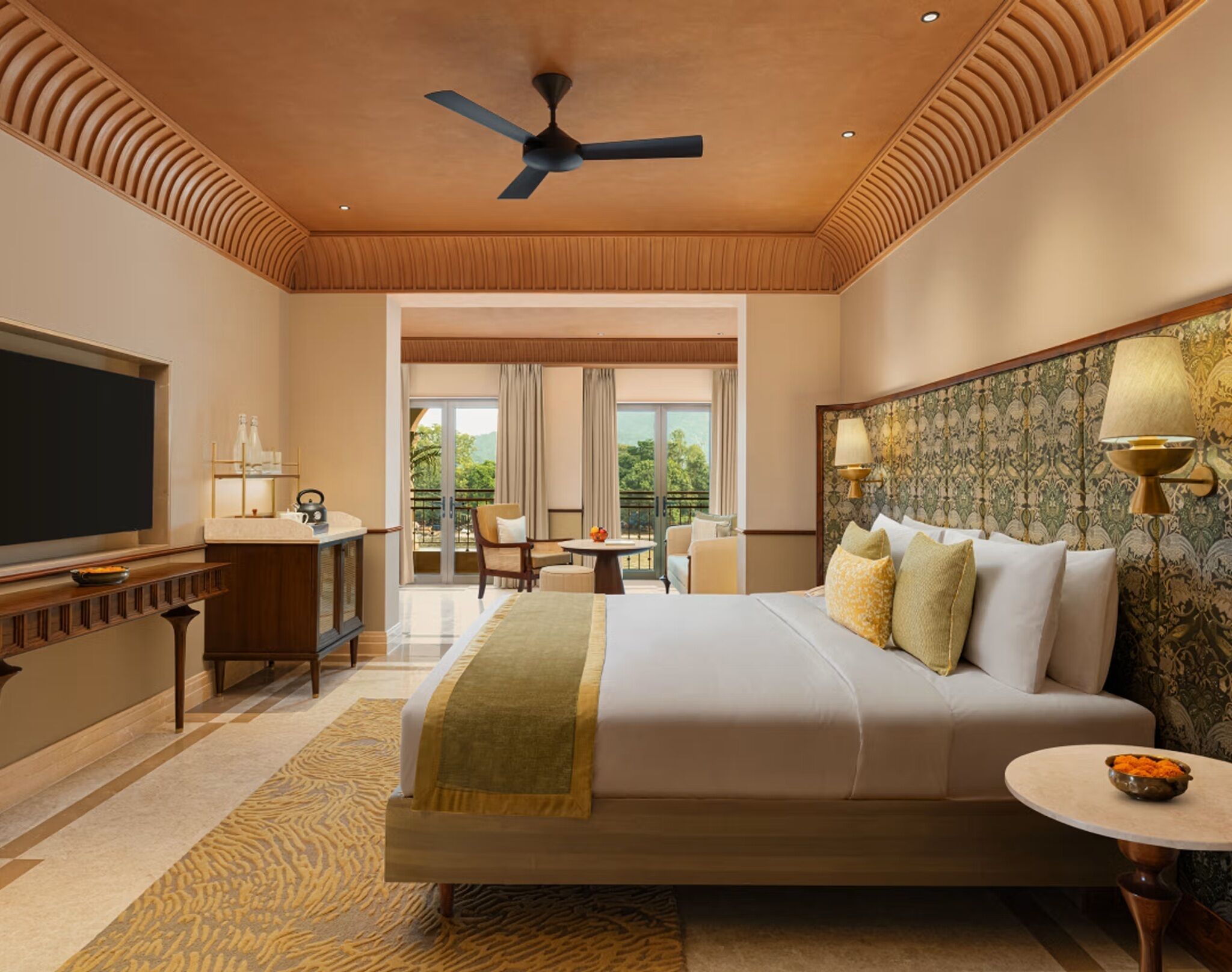 A hotel room with a large bed, a desk, a television, and a balcony with a view.