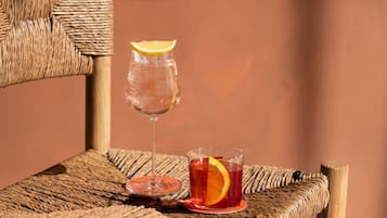 Une chaise en osier avec deux verres contenant des boissons, dont l’un est garni d’une tranche de citron.