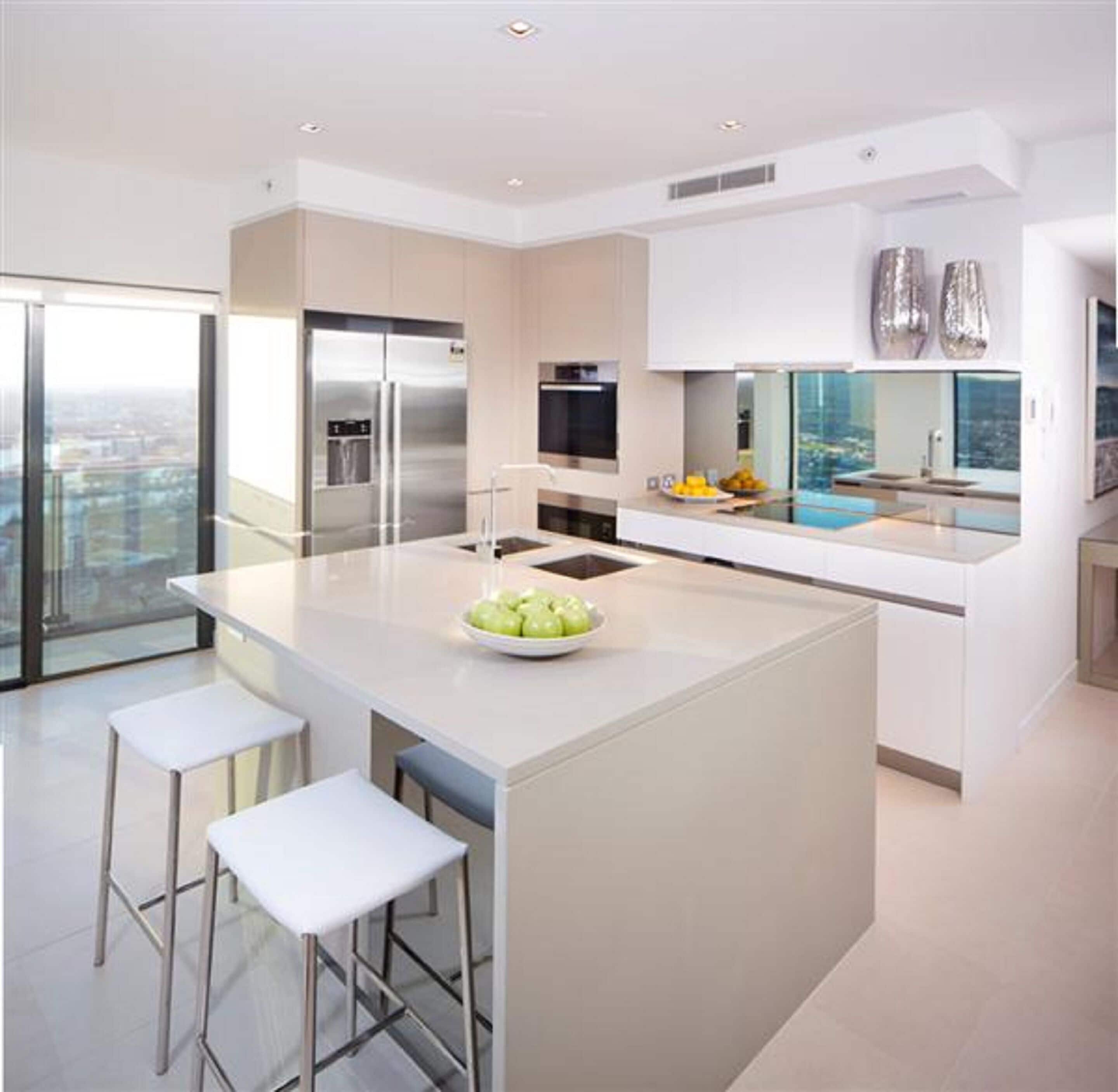 Een moderne keuken met een centraal eiland, roestvrijstalen apparatuur en een groot raam met uitzicht op een stadsgezicht.