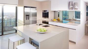 Een moderne keuken met een centraal eiland, roestvrijstalen apparatuur en een groot raam met uitzicht op een stadsgezicht.