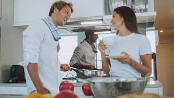 Una cocina moderna con armarios blancos, electrodomésticos de acero inoxidable y una isla central con frutas y pan.