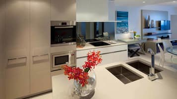 A modern kitchen with stainless steel appliances, a glass vase with flowers, and a dining area with a glass table and chairs.