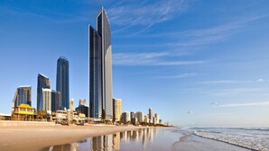 A beachfront cityscape with high-rise buildings, including a prominent skyscraper, and a sandy beach with gentle waves. - Peppers Soul Surfers Paradise (Surfers Paradise)