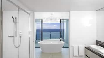 Un baño moderno con una bañera independiente, ducha y un amplio ventanal con vistas al océano.