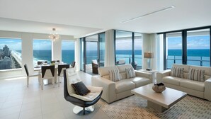 A spacious living room with a large window overlooking the ocean, a dining area with a table and chairs, and a modern chandelier. - Peppers Soul Surfers Paradise (Surfers Paradise)