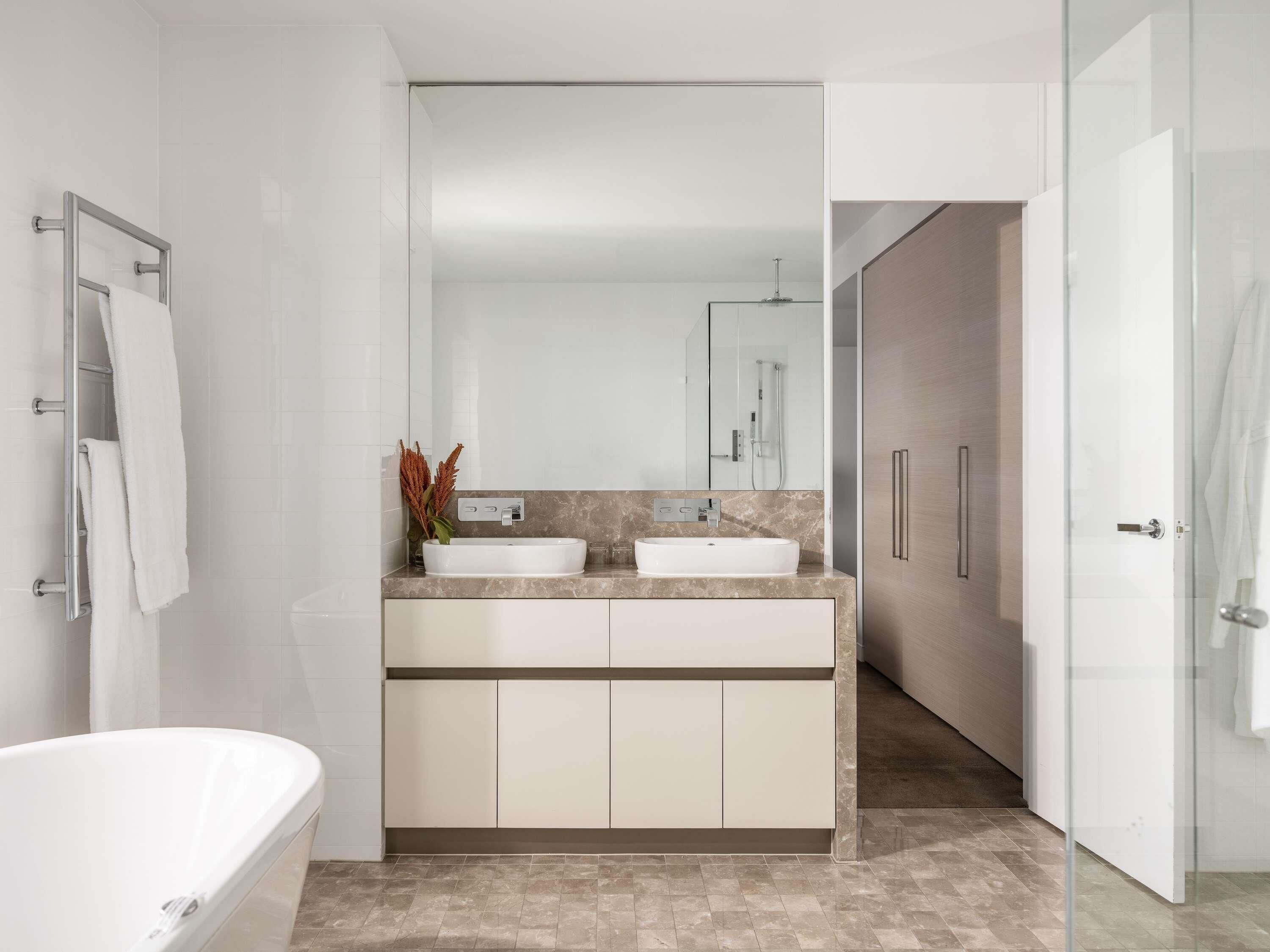 A modern bathroom with a freestanding bathtub, a double sink vanity, and a large mirror.