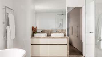 A modern bathroom with a freestanding bathtub, a double sink vanity, and a large mirror.