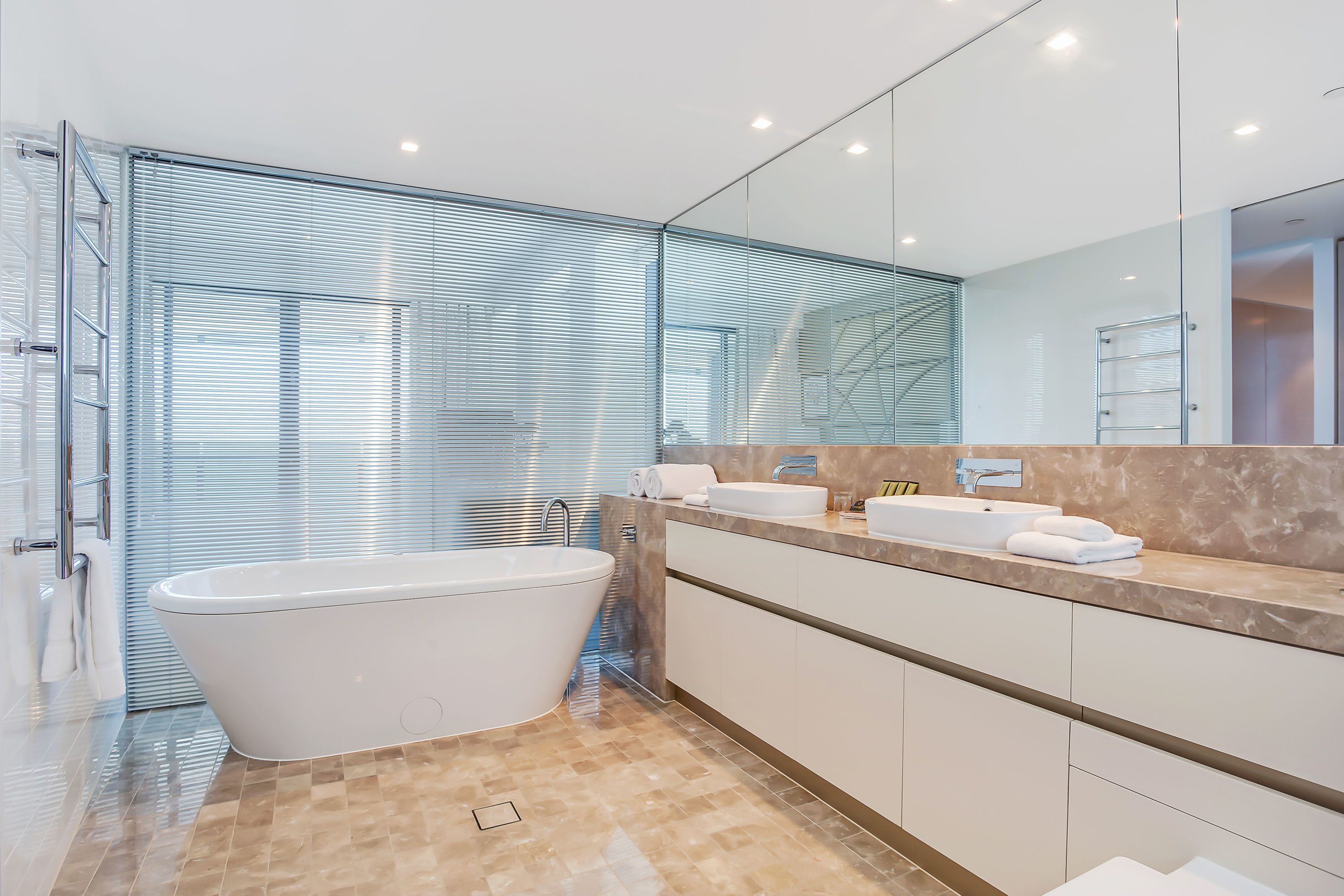 A modern bathroom with a freestanding bathtub, a large mirror, and a marble countertop.