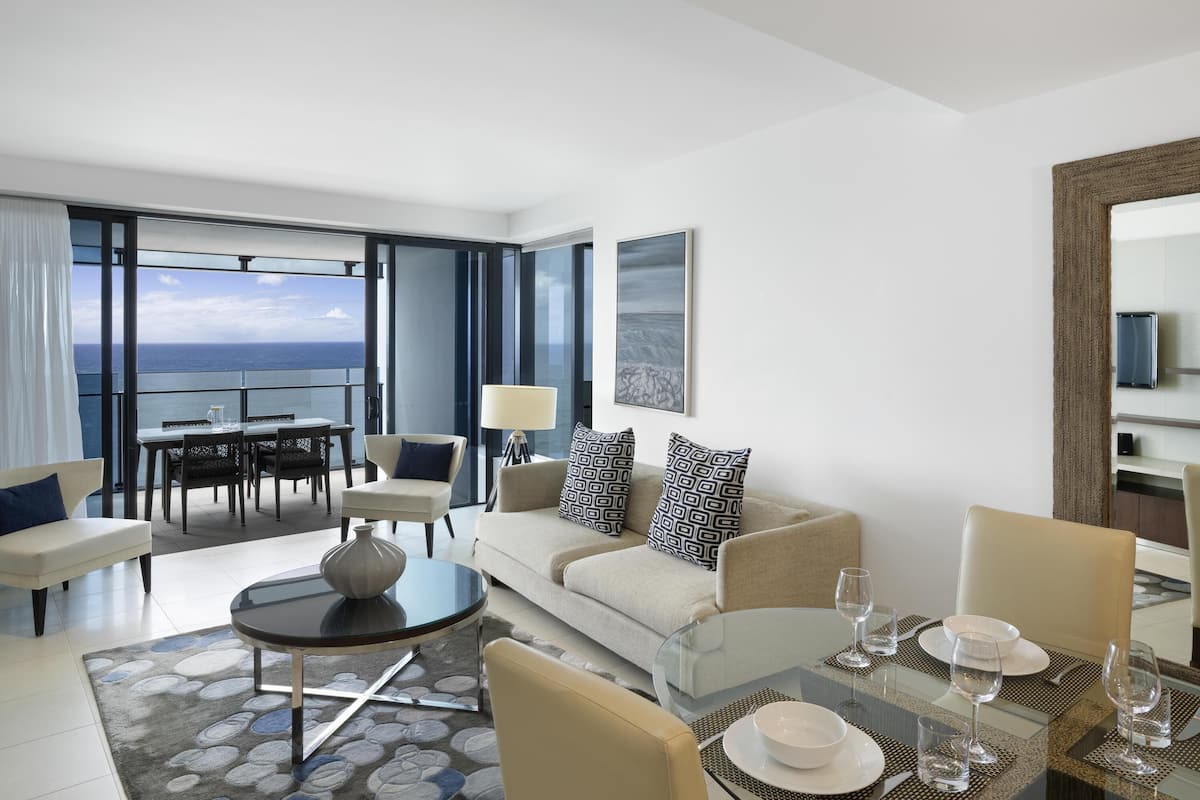 A modern hotel room with a balcony, a dining area, and a living space.