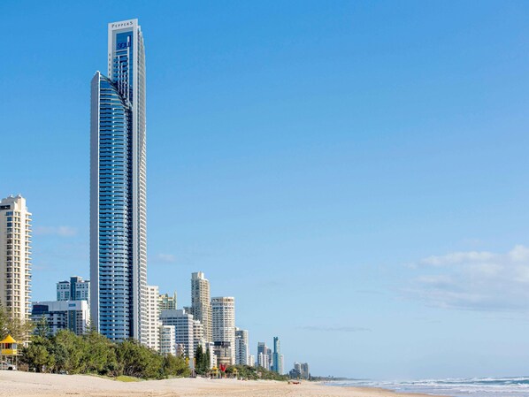 A coastal cityscape with high-rise buildings, including a prominent skyscraper with a unique design.