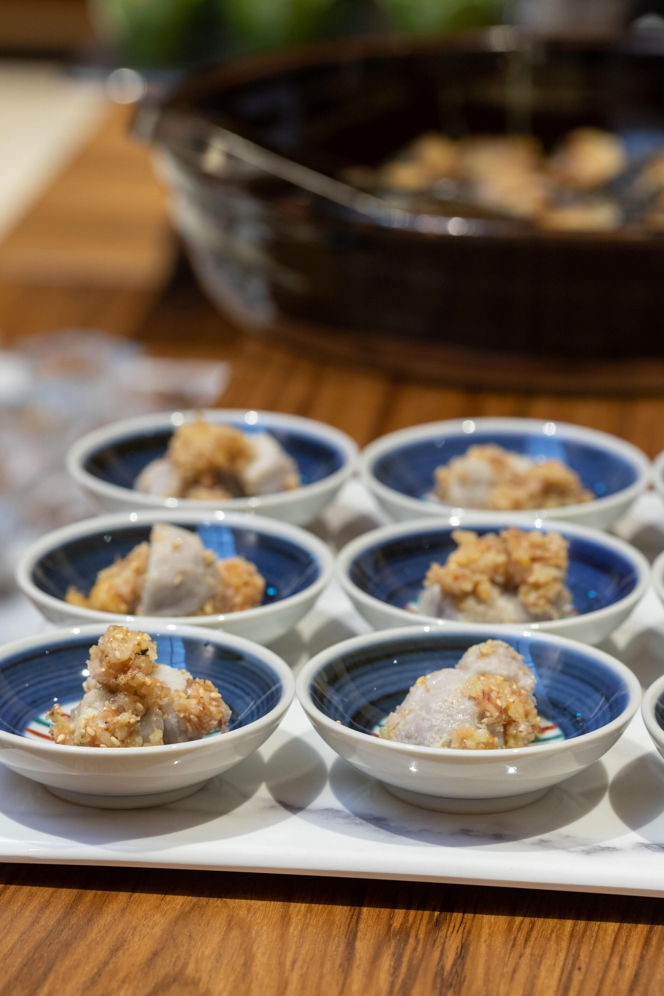 A table with several small blue bowls containing food items.