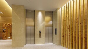 Un área de ascensor moderna con pared de paneles de madera y suelo de mármol.