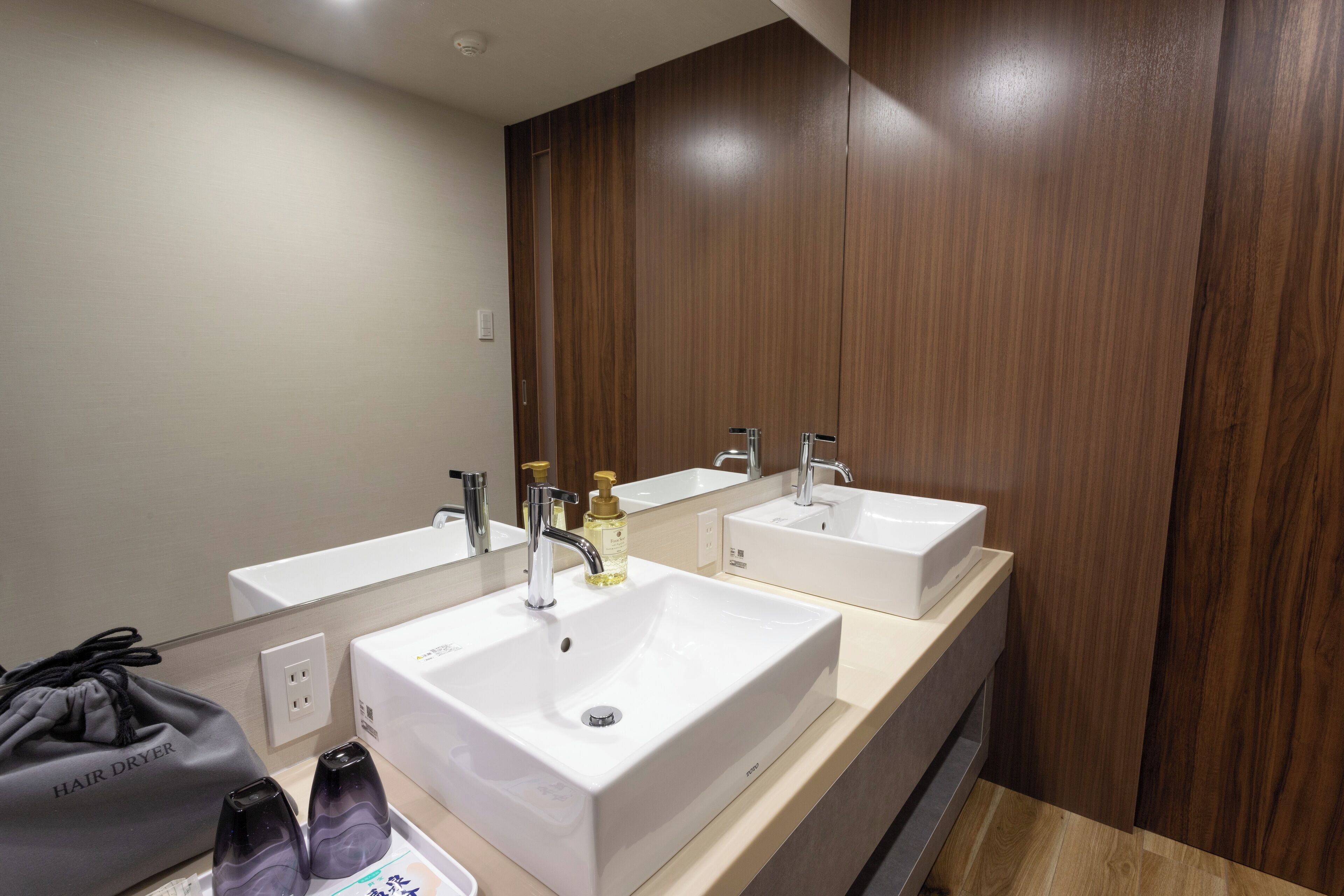 A bathroom with two sinks, a mirror, and a hair dryer on the counter.