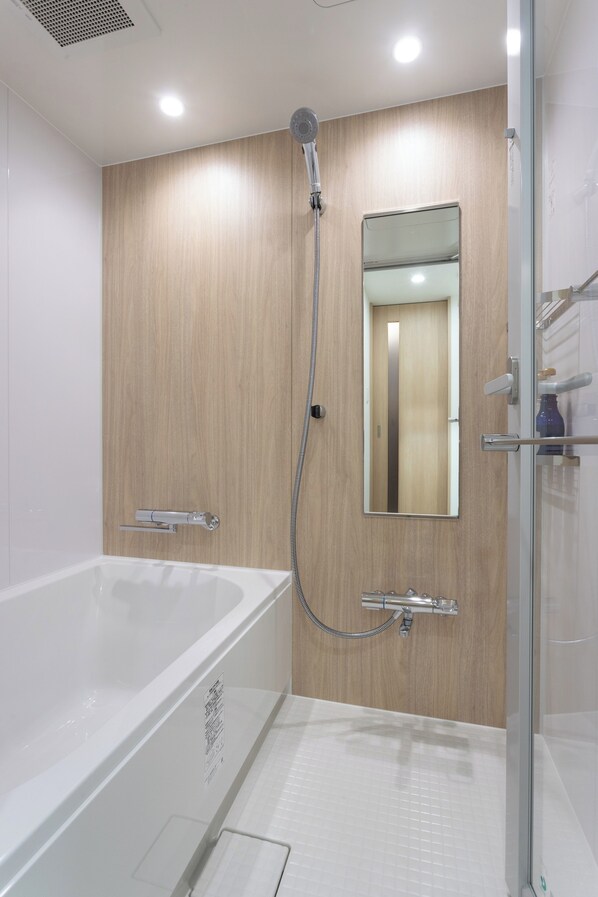 A modern bathroom with a bathtub, a shower, and a glass-enclosed shower stall. - Hotel Sundays Amami (Amami)
