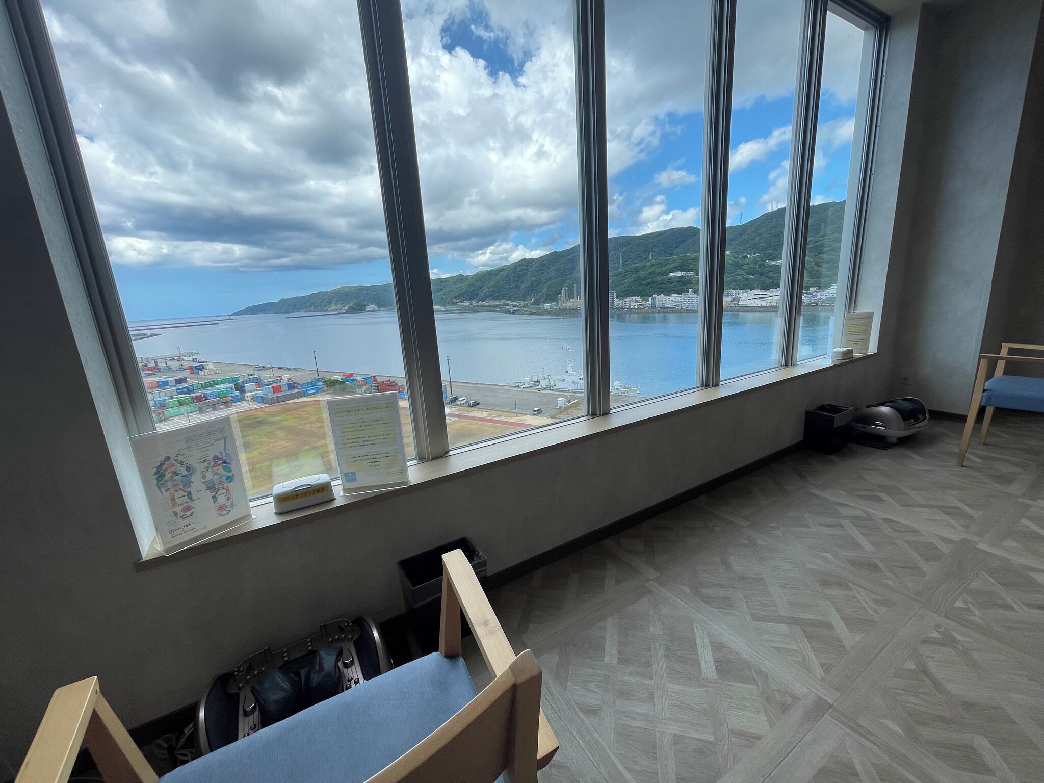 A room with a large window offering a view of a body of water and distant land.
