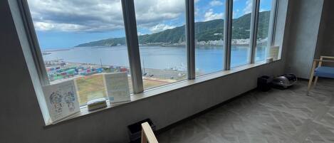 A room with a large window offering a view of a body of water and distant land.