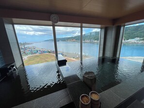 A modern indoor pool with a view of a port and mountains. - Hotel Sundays Amami (Amami)
