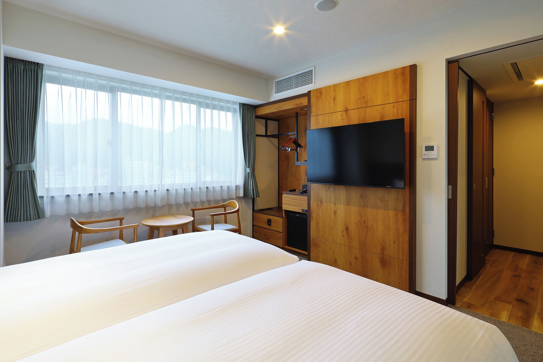 Una habitación de hotel con una cama grande, un escritorio, una silla, un televisor y un armario.