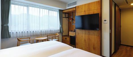 Una habitación de hotel con una cama grande, un escritorio, una silla, un televisor y un armario.