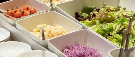 A buffet with various food items in separate containers, including tomatoes, coleslaw, and a salad.