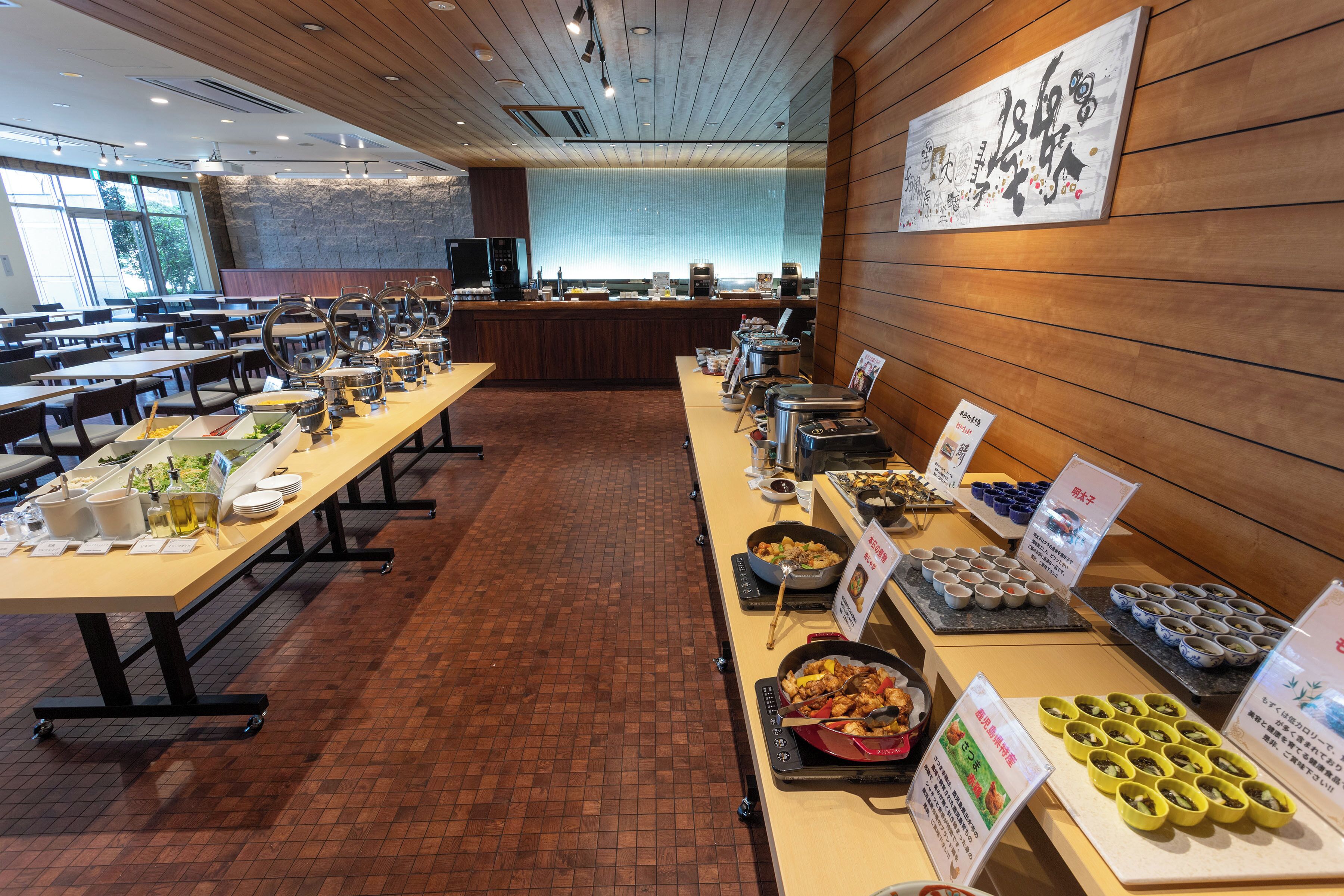 Ein reichhaltiges Buffet mit mehreren Servierstationen, einer langen Theke voller Speisen und einem Sitzbereich mit Tischen und Stühlen.