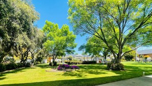 A well-maintained garden with a lawn, a central flower bed, and a seating area with chairs and a table. - Nagambie Motor Inn (Nagambie)