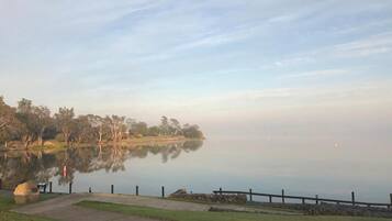 A calm lake with a wooden dock and a stone wall.