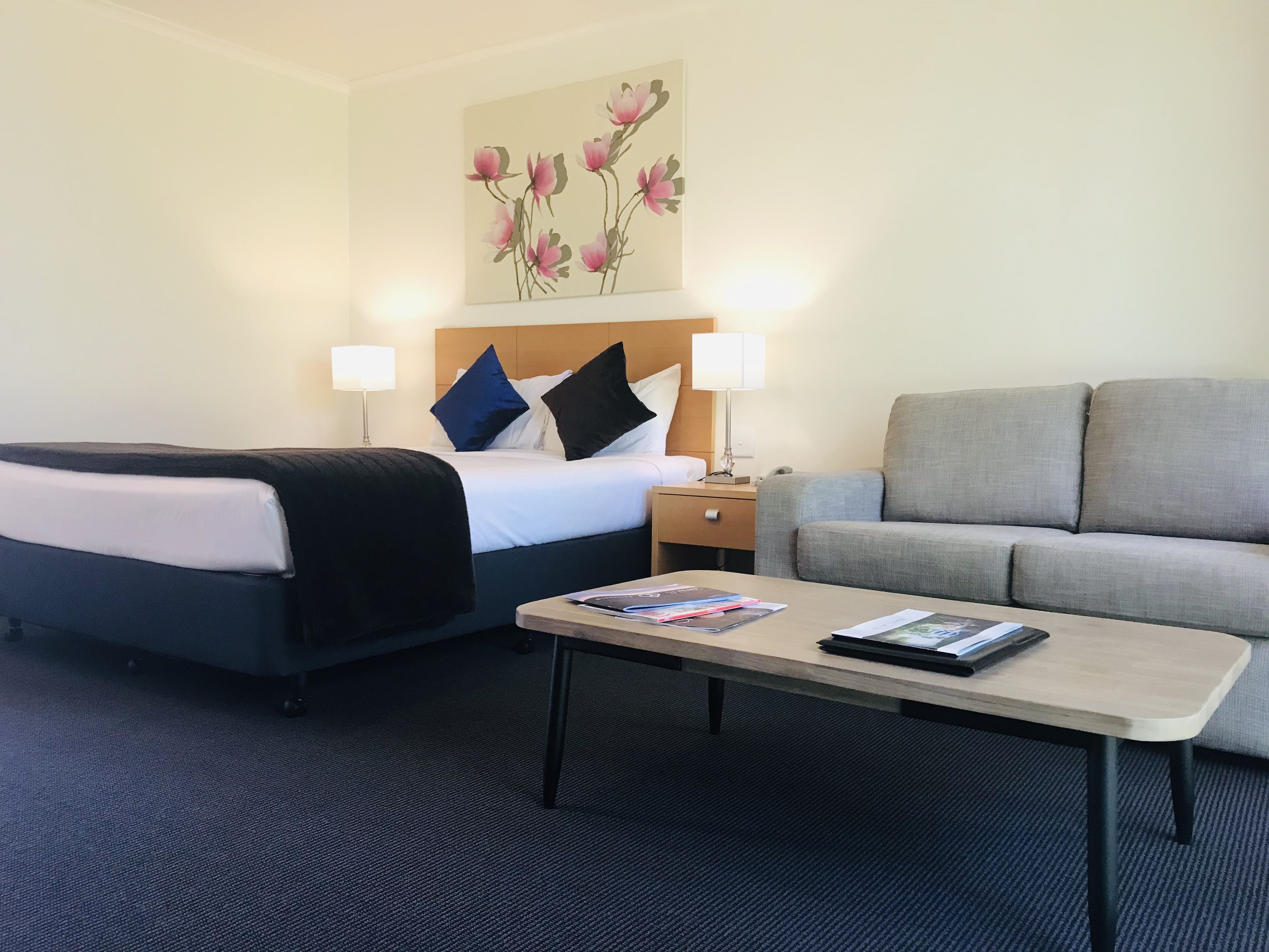 A hotel room with a bed, two bedside lamps, a sofa, and a coffee table.
