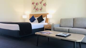 A hotel room with a bed, two bedside lamps, a sofa, and a coffee table.