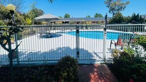 A fenced swimming pool area with a view of a building in the background. - Nagambie Motor Inn (Nagambie)
