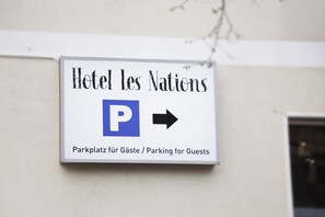 A sign for Hotel les Nations indicating guest parking.