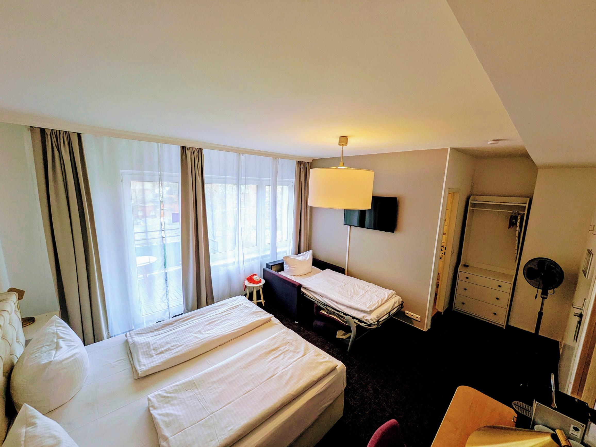 A hotel room with a bed, bedside table, lamp, TV, and a walk-in closet.