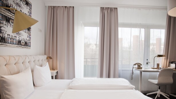 Habitación de hotel con una cama grande, un escritorio y vistas a la ciudad desde la ventana.