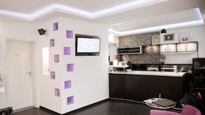 Un moderno vestíbulo de hotel con una recepción, una televisión y una zona de bar.
